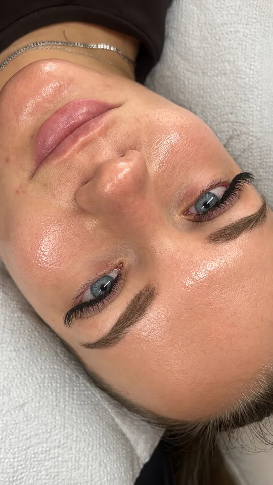 Geschwungene Wimpernextensions bei blauen Augen auf der Behandlungsliege