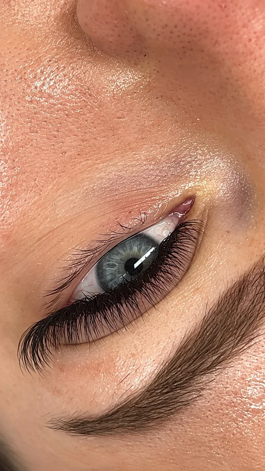 Seitliche Detailaufnahme von Wimpernextensions an einem blauen Auge