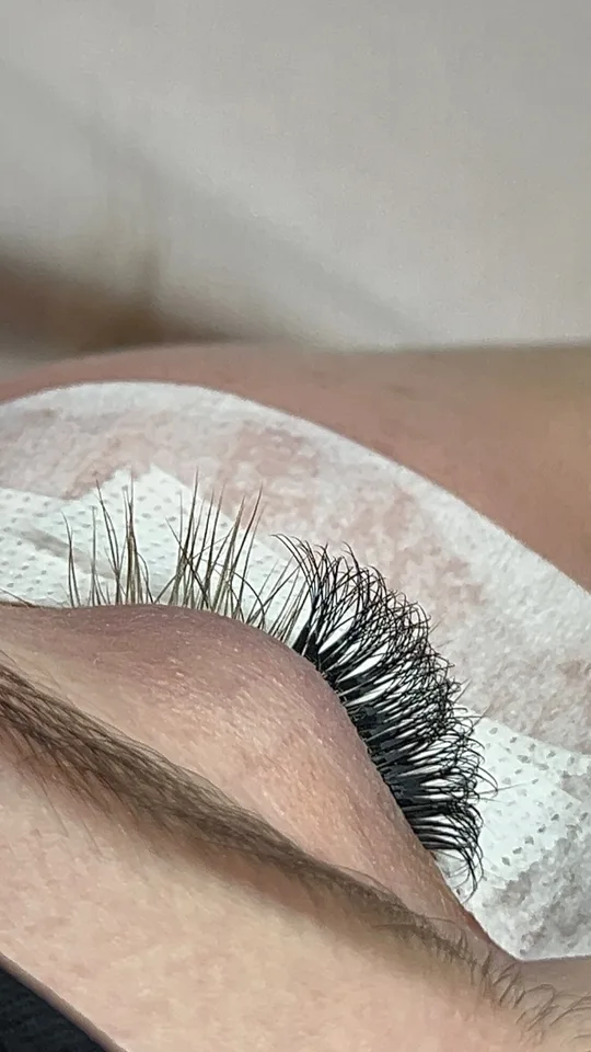 Seitliche Nahaufnahme der Wimpernfächer mit Augenpad während der Behandlung
